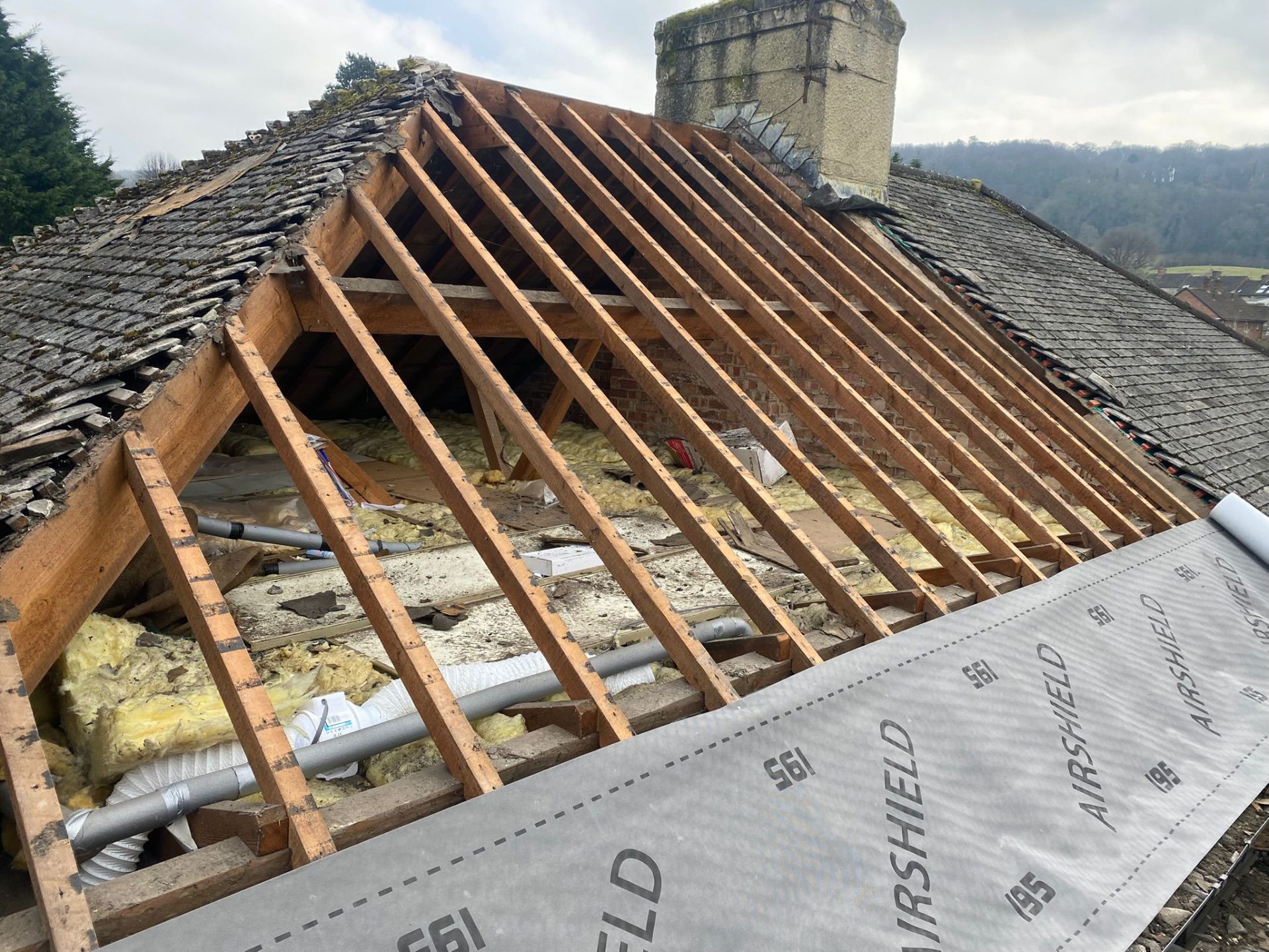 Professional roofer installing breathable membrane and battens on a Cotswold stone property roof
