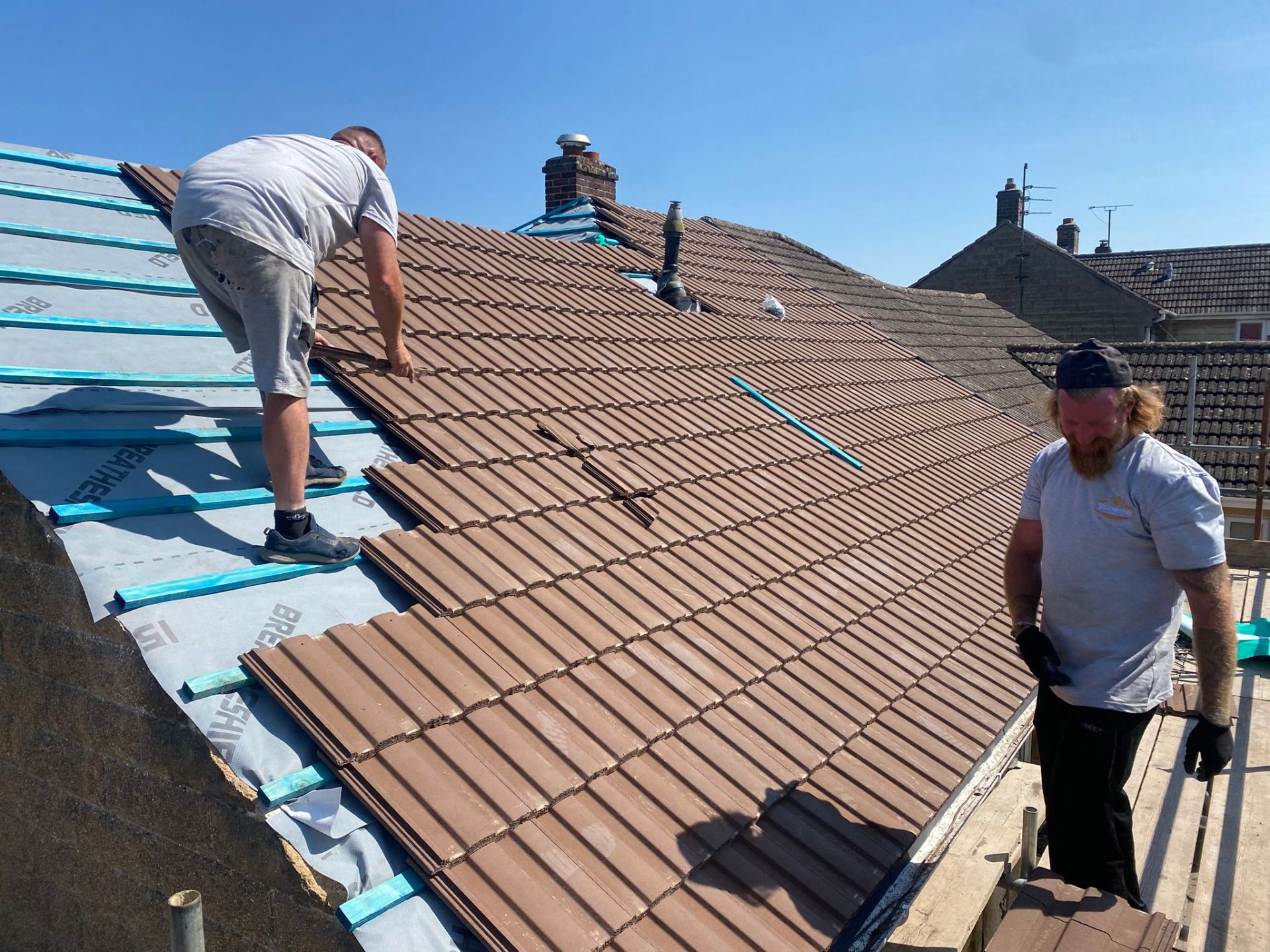 New interlocking roof tiles being installed during a complete roof replacement